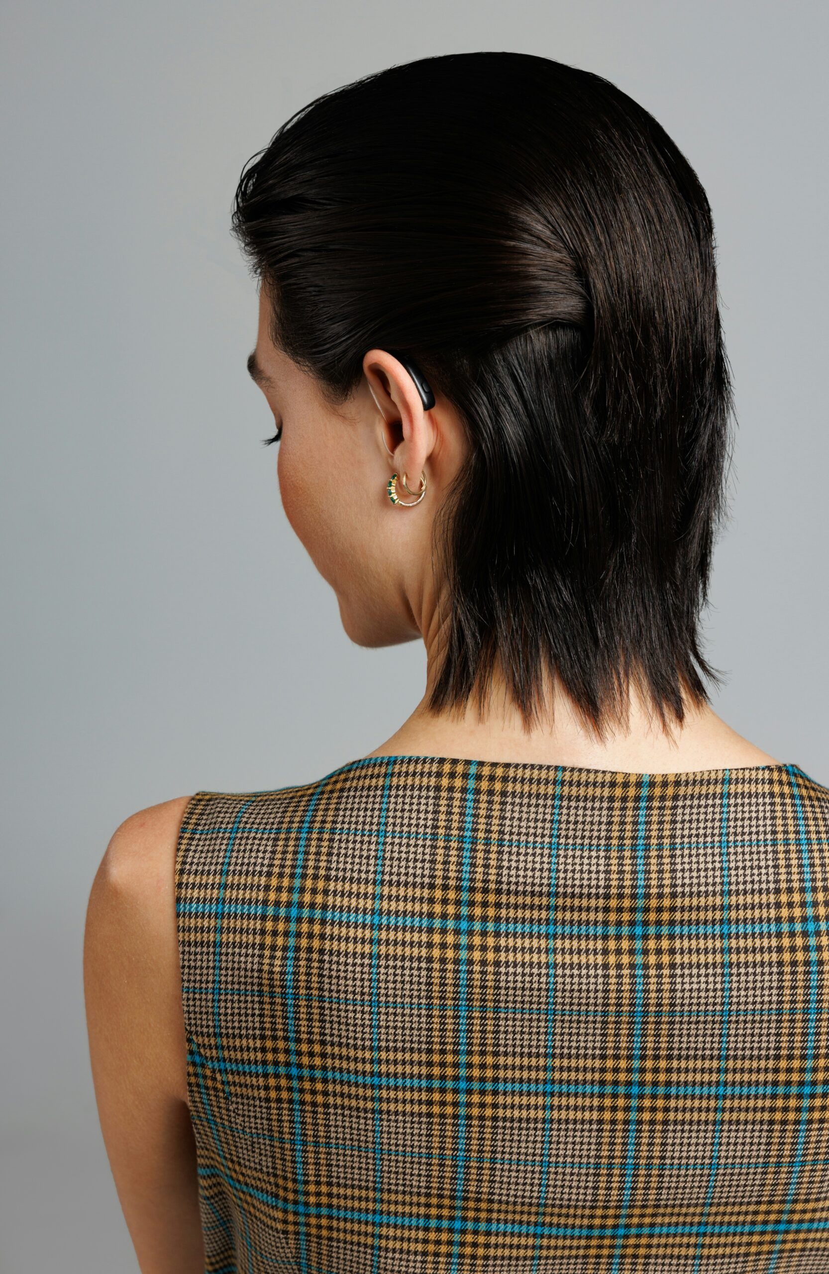 a woman with a short black hair wearing a plaid dress